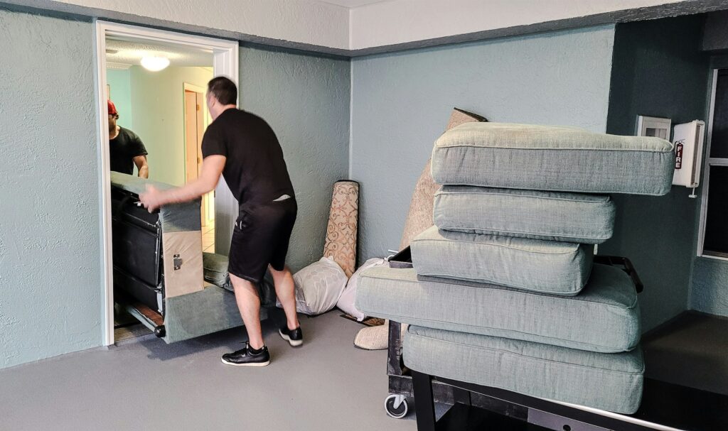 Millennial son gets help from friend who is a Furniture mover to load a sofa on truck downstairs.